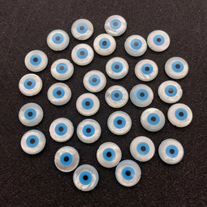 Détail macro de perles rondes en nacre avec motif œil grec pour la création de bijoux