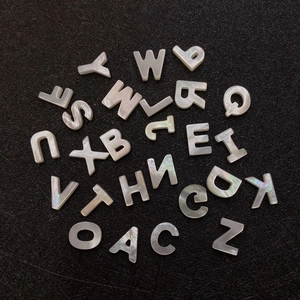 Natural white mother of pearl alphabet beads A-Z for DIY jewelry on black background