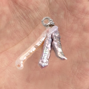 Dettaglio macro di perle barocche naturali in castone a griffe su un gancio in argento