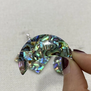 Gros plan d'un pendentif en nacre d'abalone en forme de lune avec des reflets arc-en-ciel