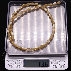 Champagne gold teardrop shell beads on an electronic scale showing product weight