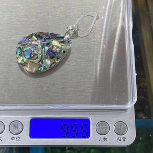 Vue détaillée d'un pendentif goutte en nacre d'abalone sur une balance pesant 9,55g