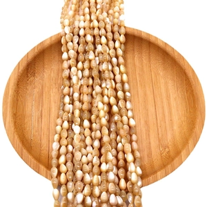 Natural shell champagne teardrop beads on a wooden tray for DIY necklace making