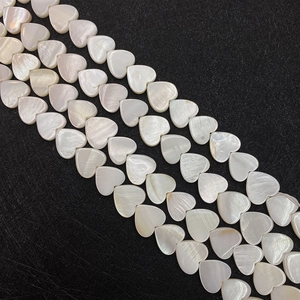 Macro shot of heart-shaped natural shell beads with iridescent luster on black background
