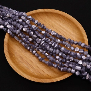 Macro shot of 4-6mm irregular purple shell beads on a wooden tray for DIY jewelry