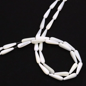 Detalle macro de cuentas de concha blanca en forma de gota con brillo natural de nácar