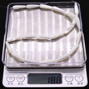 Macro shot of natural teardrop mother of pearl shell beads weighing 18.8g on a digital scale
