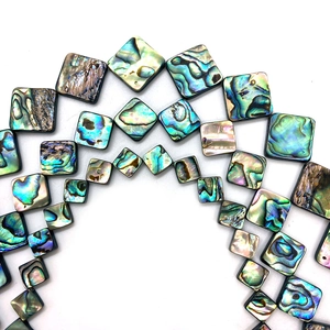 Macro shot of square natural abalone shell beads with iridescent peacock green and blue luster
