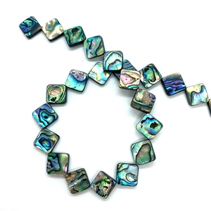 Macro shot of square natural abalone shell beads with vibrant multi-color iridescent texture