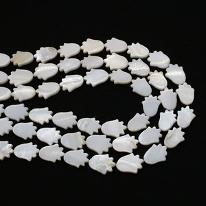 Macro detail of white mother of pearl Hamsa hand beads for DIY jewelry making with luster
