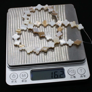 Macro view of four-leaf clover natural shell beads showing weight 16.2g on digital scale