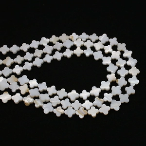 Macro detail of white natural shell beads in a clover shape with pearlescent finish