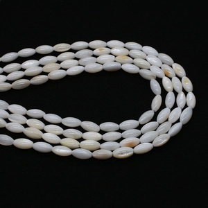 Macro detail of white oval freshwater shell beads with natural luster on black background