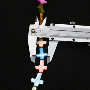 Macro shot measuring 10mm colorful freshwater shell cross beads with a digital caliper