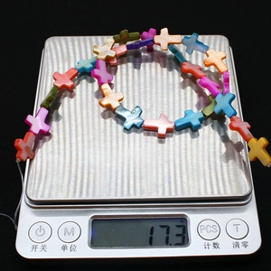 Macro shot of colorful cross-shaped freshwater shell beads for DIY jewelry on a scale