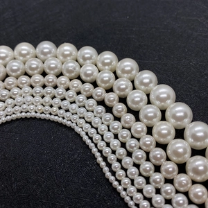 Multiple sizes of white imitation pearl beads for DIY jewelry making on black background
