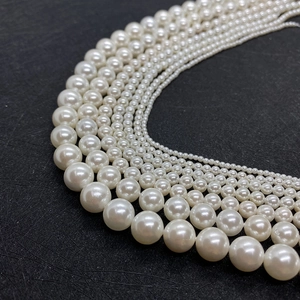 Multiple sizes of creamy white faux pearls arranged in arcs on black background