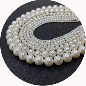 Lustrous white faux pearl beads in various sizes displayed on a premium black background
