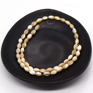 Natural sea shell rice beads 4x8mm for jewelry making on black ceramic tray