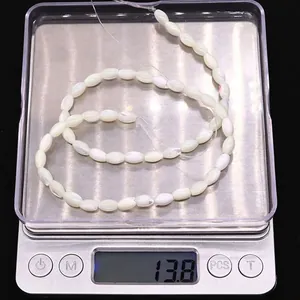 Makroaufnahme von Naturmuschel-Spindelperlen mit 13,8 g Gewicht auf einer digitalen Waage