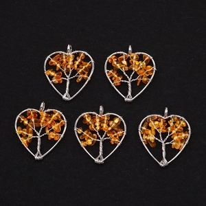 Detail view of five silver wire wrapped heart pendants with orange stone tree of life design