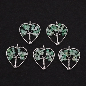 Detailed macro view of heart-shaped Tree of Life pendants with silver wire and green stones