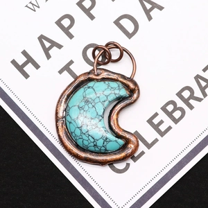 Macro shot of turquoise moon pendant with vintage bronze plating and double ring bail