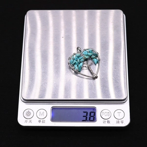 Macro shot of a heart-shaped tree of life stone pendant on a silver scale weighing 3.8g