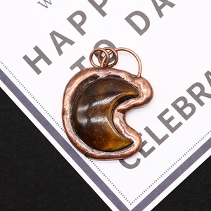 Macro shot of tiger eye stone moon pendant with bronze plating and textured metal edges