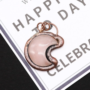 Macro view of rose quartz crescent moon pendant with vintage copper metal frame