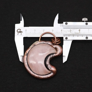 Measuring a crescent moon natural stone pendant with calipers to show 4.2cm width