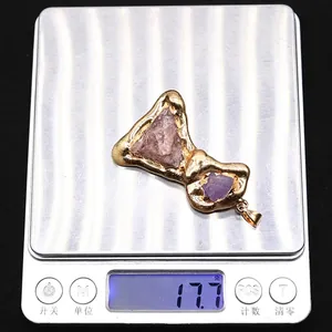 Bow-shaped metal pendant with natural stones on a digital scale weighing 17.7 grams