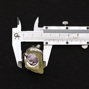 Detailed macro view showing a 25mm green fluorite pendant with amethyst stone