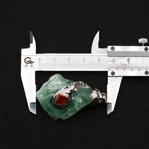 Macro shot of natural green stone pendant with silver edging measured by a caliper