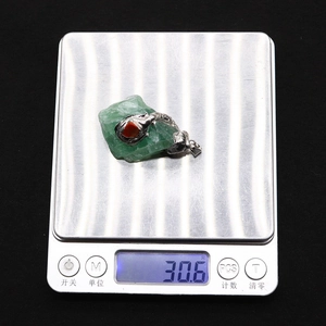 Detailed close-up of a green gemstone pendant weighing 30.6g on a digital scale