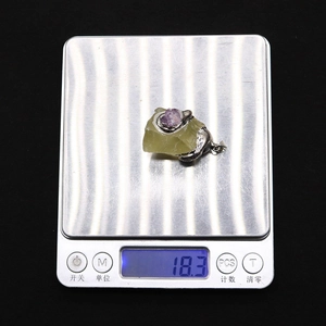 Detail shot of a natural green stone and amethyst pendant weighing 18.3g on a scale