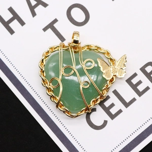 Close-up of heart-shaped green stone pendant with gold wire wrap and butterfly charm
