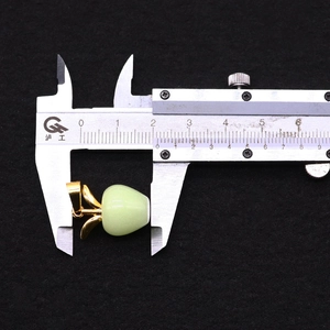 Schuifmaat meet de 15 mm breedte van de lichtgroene appelvormige stenen hanger
