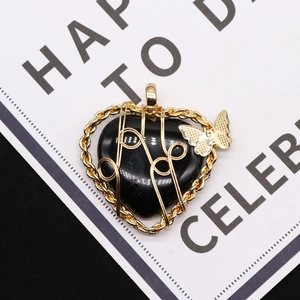 Macro shot of heart-shaped black stone pendant with gold wire wrap and butterfly detail