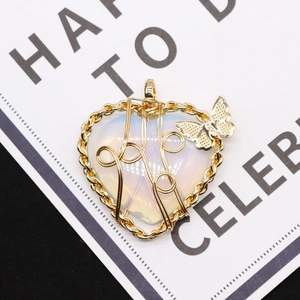 Macro shot of heart-shaped opal pendant with golden wire wrap and butterfly detail
