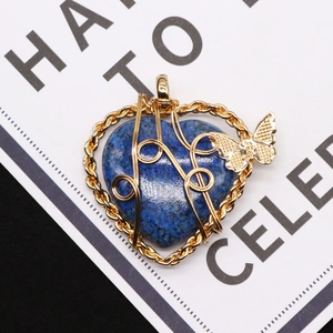 Macro view of heart-shaped blue natural stone pendant with gold wire wrap and butterfly