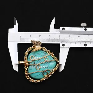 Macro shot measuring heart-shaped turquoise pendant with golden butterfly and wire wrap