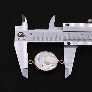 Macro shot of a Baroque coin pearl connector with gold plating measured with calipers