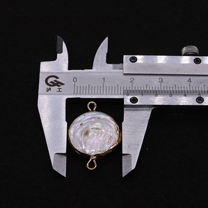 Macro detail of 18mm round freshwater pearl pendant with gold plating and connector rings