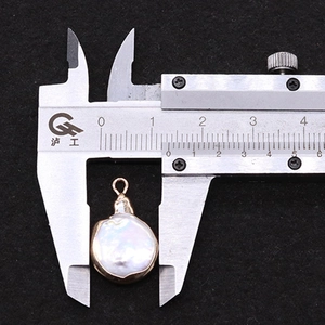 Macro-opname van 18mm barokke parelhanger met vergulde randen en een metalen schuifmaat