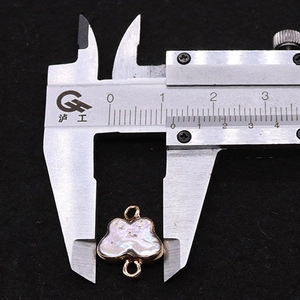 Macro shot showing butterfly pearl pendant measurement with a caliper for DIY jewelry