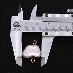 Macro shot of baroque pearl connector with gold edges measured by digital caliper