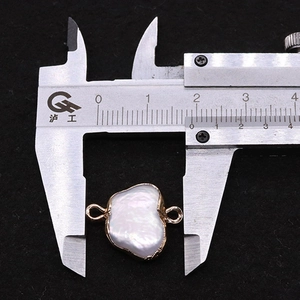 Macro detail of butterfly baroque pearl pendant with gold plating and measurement scale