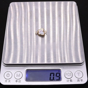 Detailed view showing a 0.9g butterfly shape pearl pendant on a digital scale