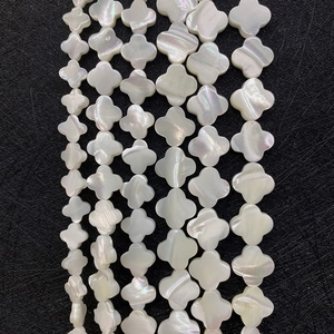 Macro shot of clover-shaped white mother of pearl beads with iridescent luster for jewelry DIY